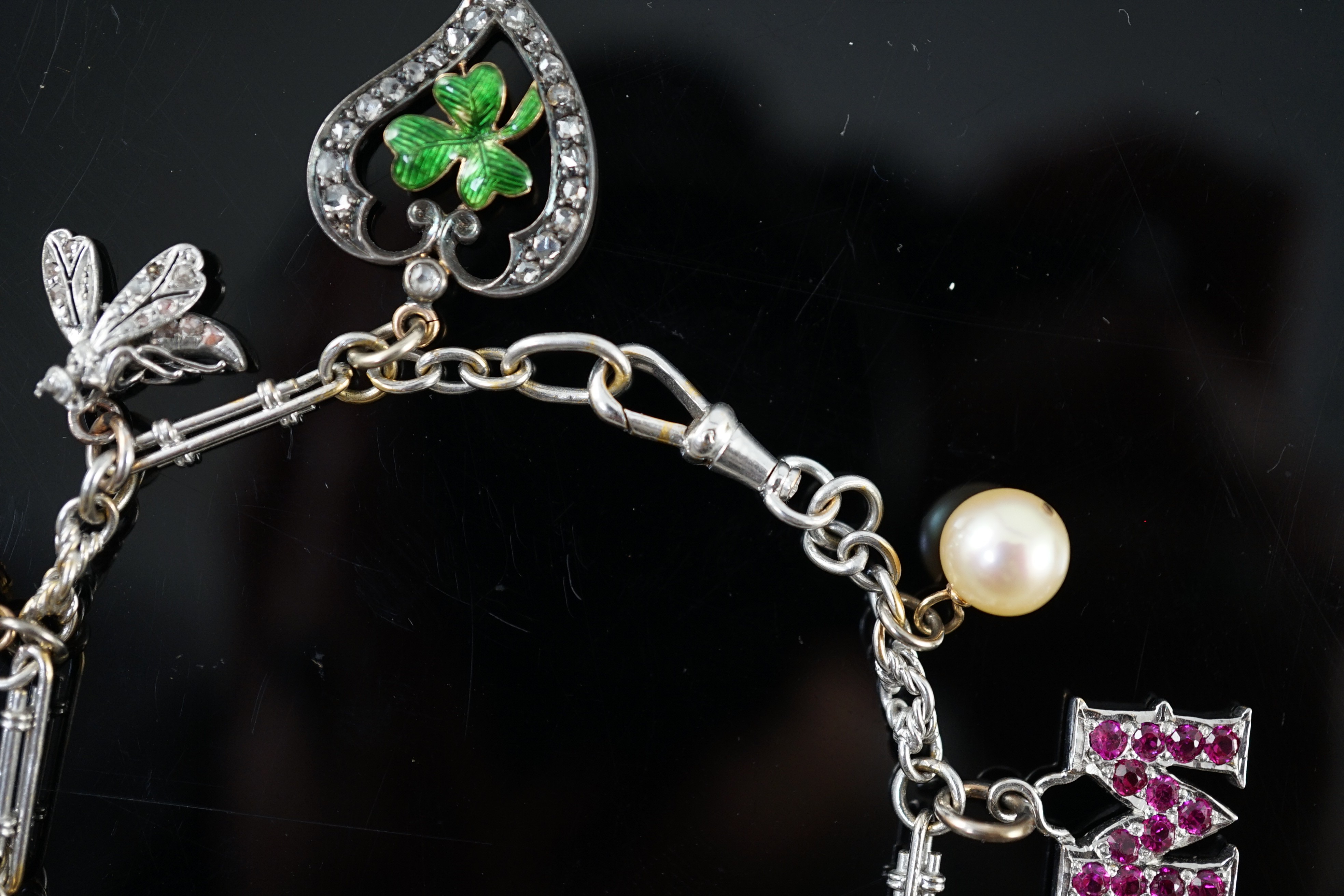 A French 18ct white gold circular and baton link charm bracelet, hung with eleven assorted charms